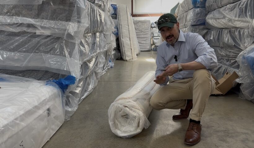 Cut open bed-in-a-box hybrid mattress showing weak coils, low-density foam layers, and minimal edge support compared to a commercial-grade store-bought mattress.